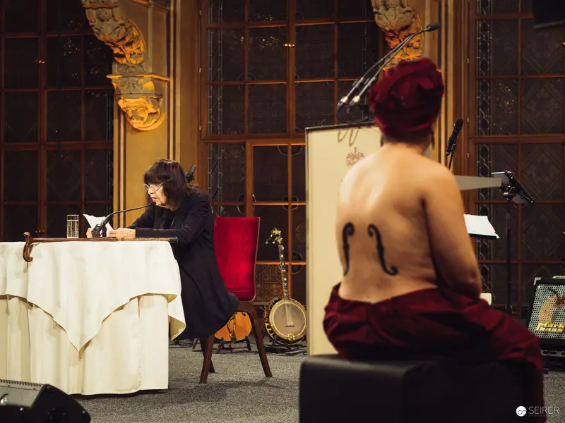 Performance Stage Scene with Seated Performer and Writing Participant