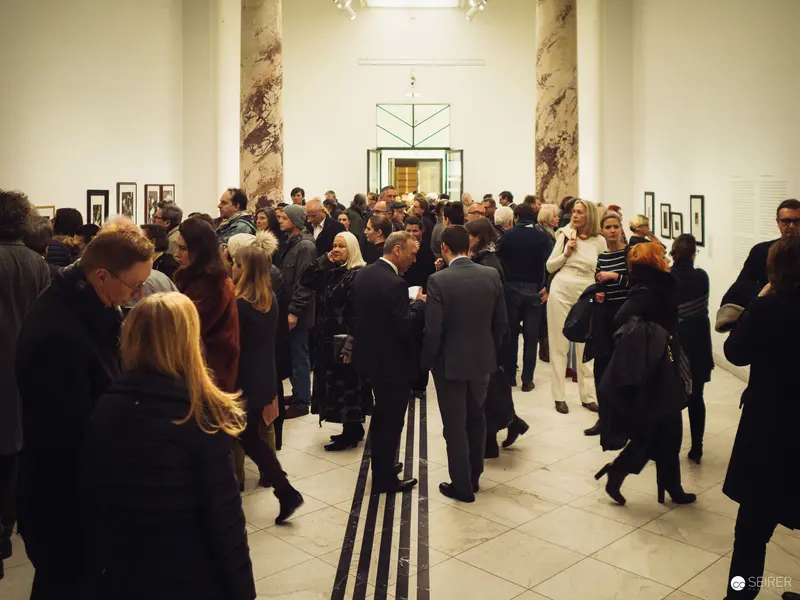 Gallery Opening: Crowded Exhibition Space with Marble Columns and Attendees