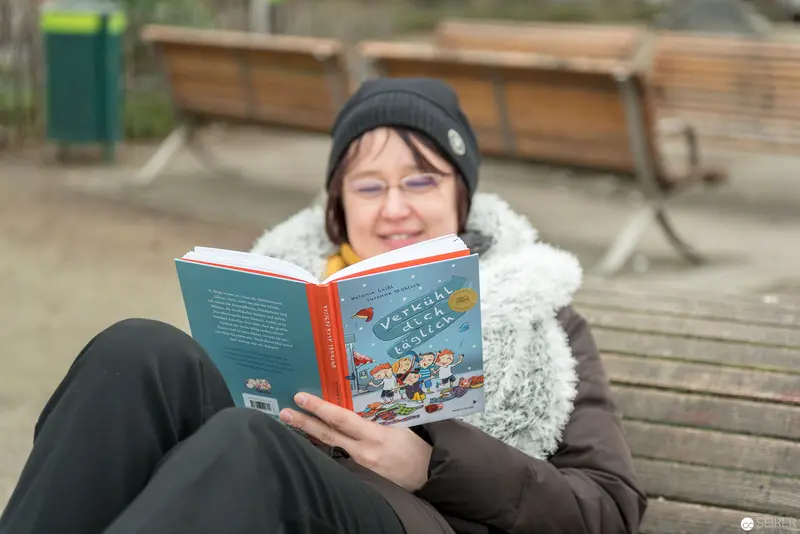 Janett Cernohuby Reading Outdoors in Cozy Winter Attire at Vienna Public Library Park