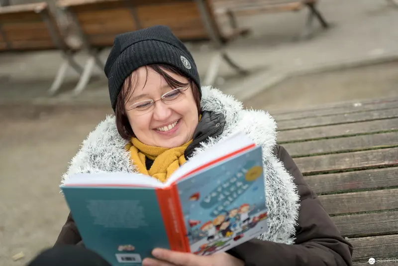 Janett Cernohuby Reading in Winter, Bundled in Cozy Layers at Vienna Public Library Park