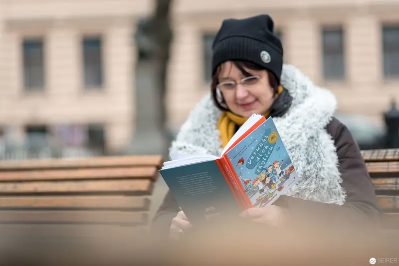 Janett Cernohuby Reading Outdoors in Cozy Winter Attire near Vienna's Main Library
