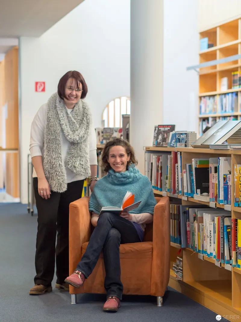 Two Librarians in Contemplative Study amid Bookshelves and Architectural Spaces
