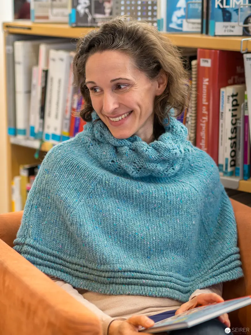Scholar in Blue Knit Cowl Reading Among Bookshelves