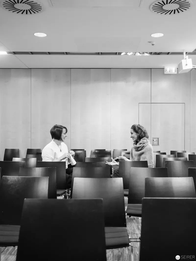 Melanie Laibl in Contemplative Dialogue Amidst Vacant Conference Space