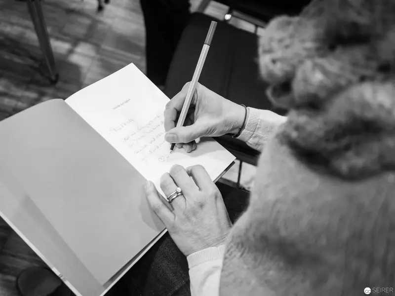 Melanie Laibl Authographing Book during Literary Event in Black and White
