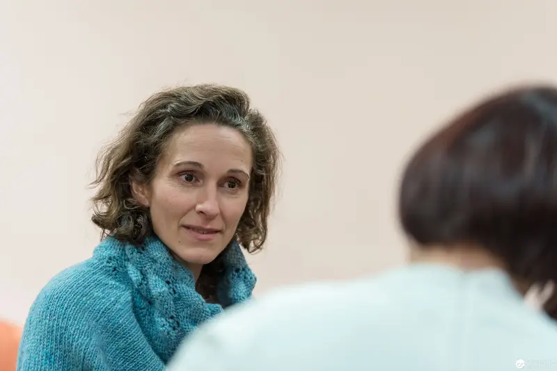 Woman in Teal Sweater Engaged in Attentive Conversation