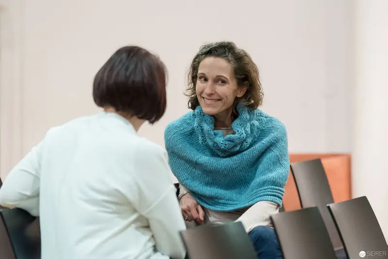 Two Women in Conversation, Professional Interior Setting with Turquoise Accent