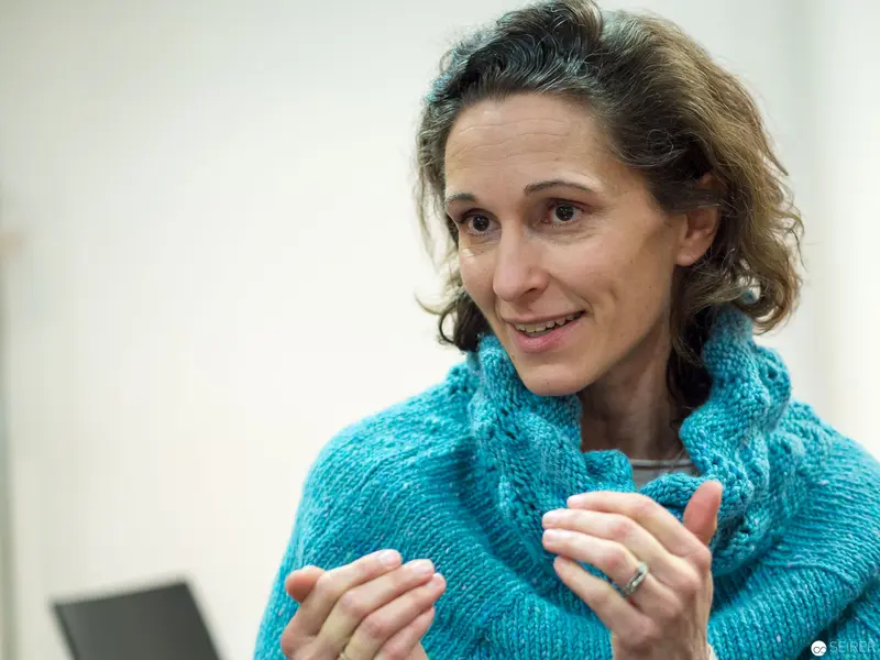 Woman in Turquoise Knitted Sweater Gesturing During Presentation