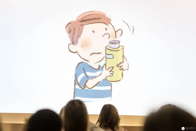 Child Examining Yellow Bottle During Illustrated Presentation