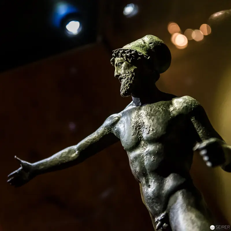 Bronze Sculpture of Classical Male Figure in Dramatic Lighting at Museum Event