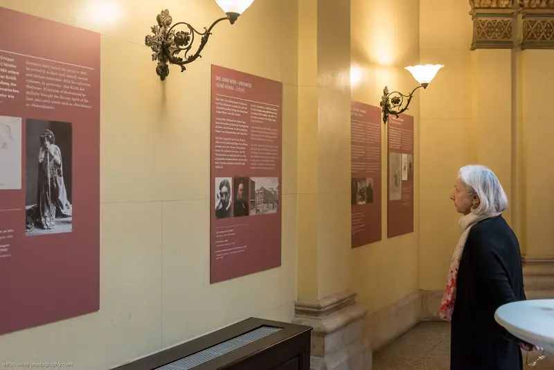 Elderly Woman Studying Historical Exhibition Panels in Contemplative Silence