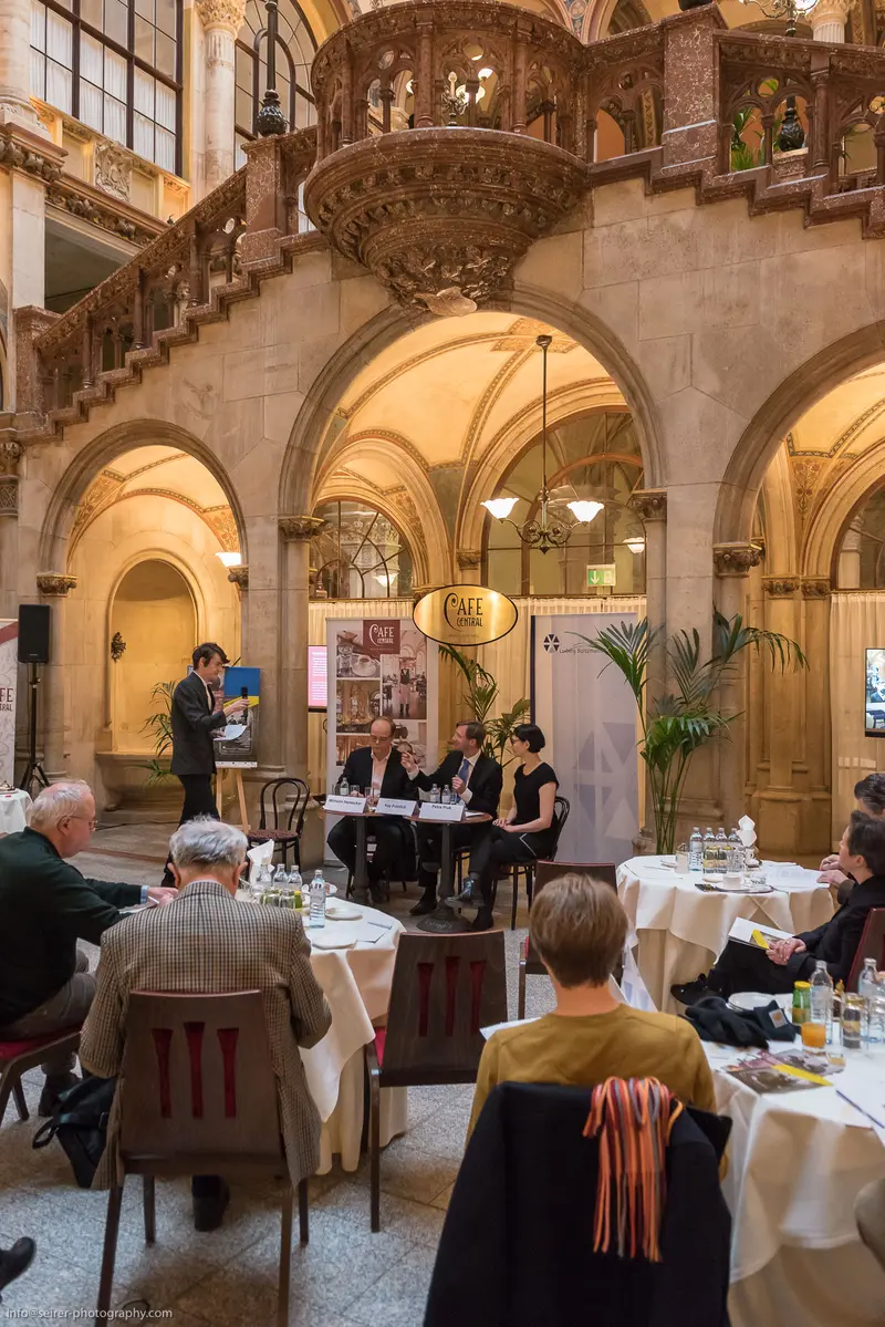 Historical Venue Interior with Panelists at Formal Event in Ornate Architectural Setting