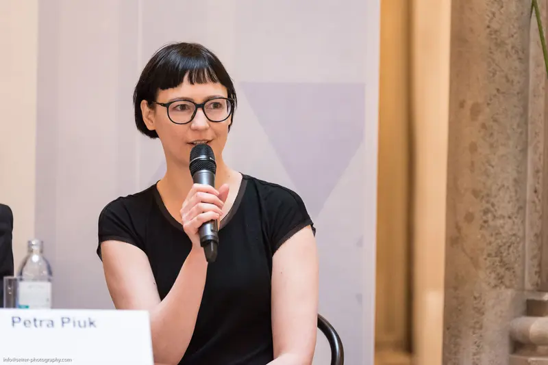 Speaker in Black Presenting at Conference with Microphone and Glasses