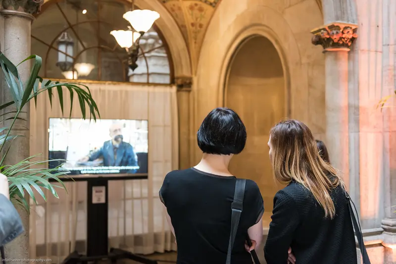 Two Viewers Observing a Video Display in Ornate Architectural Setting
