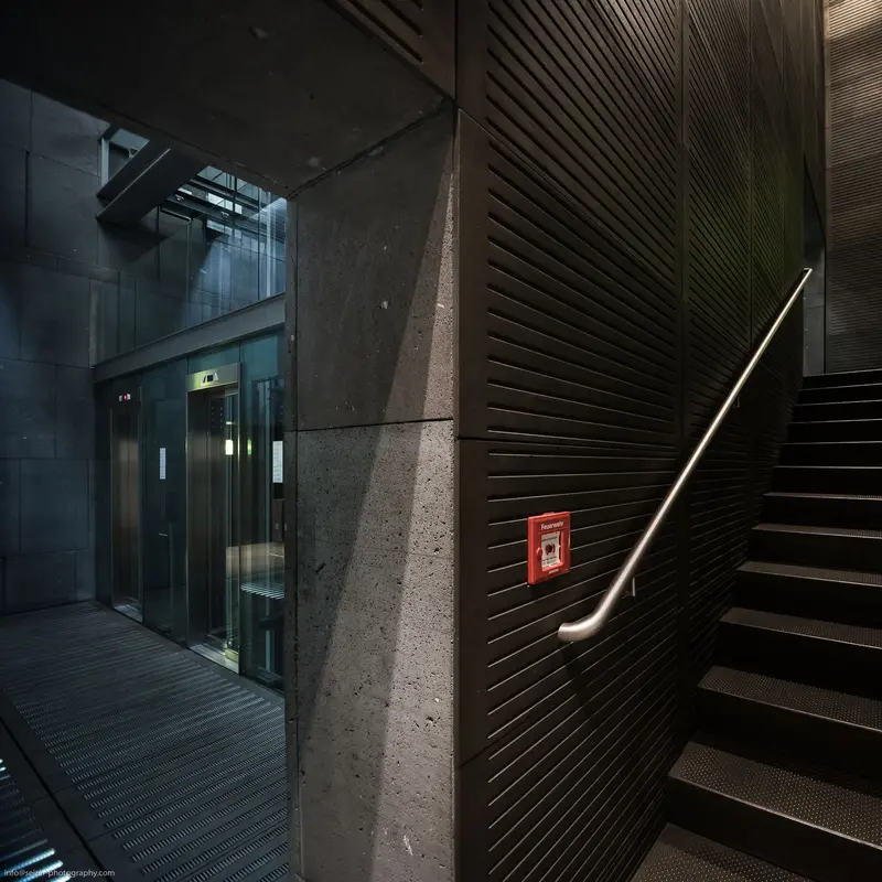 Architectural Interior with Staircase, Concrete Wall, and Emergency Exit Sign