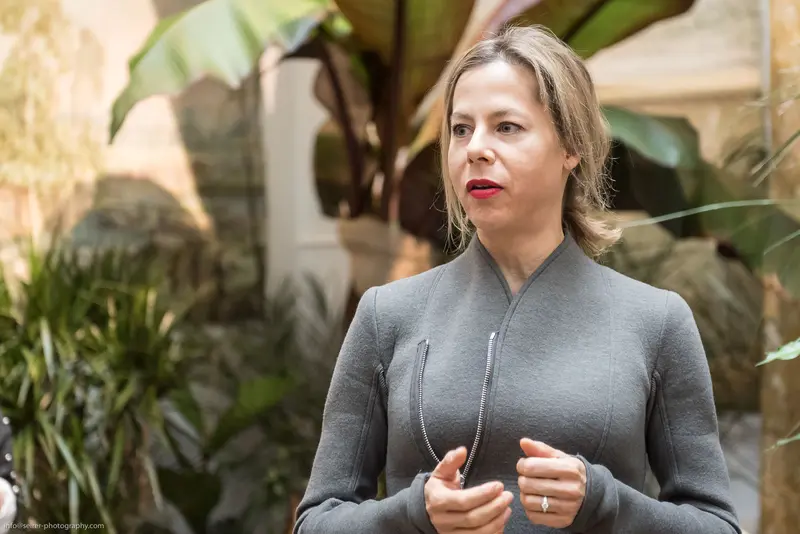 Mid-Career Professional in Grey Knit Sweater Amid Indoor Botanical Setting