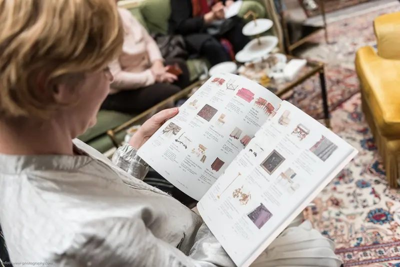 Reading Catalog in Cozy Interior with Decorative Patterned Rug and Seating