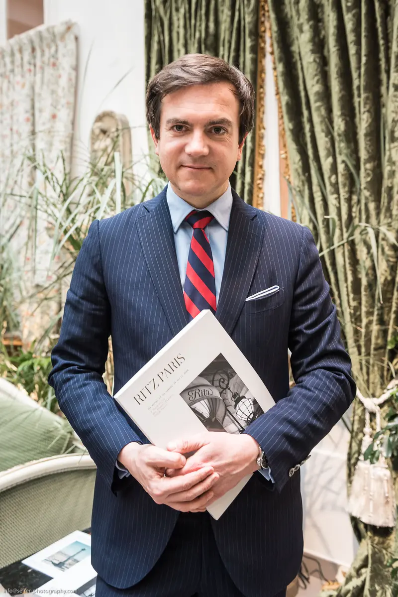Professionally Attired Man Holding Literary Magazine in Elegant Interior Setting