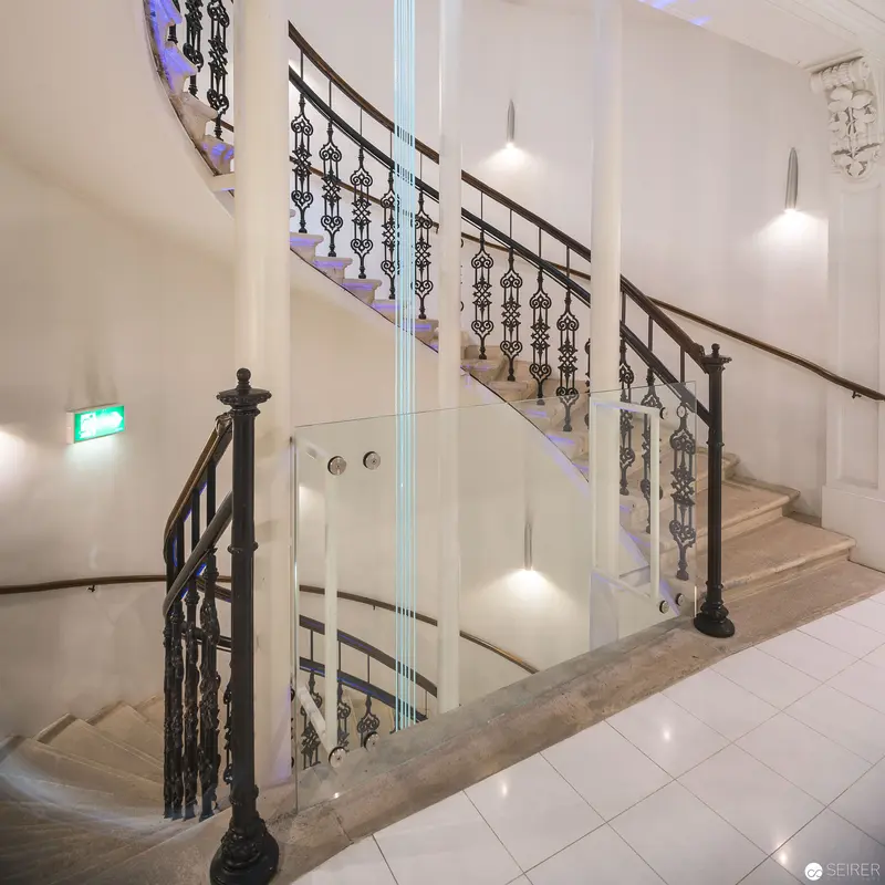 Ornate Staircase with Decorative Metalwork and Illuminated Glass Panels