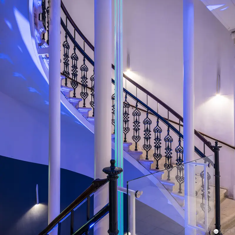Ornate Staircase with Blue Architectural Lighting and Decorative Railings