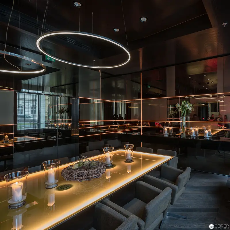 Intimate Dining Space with Circular Lighting and Reflective Dark Surfaces