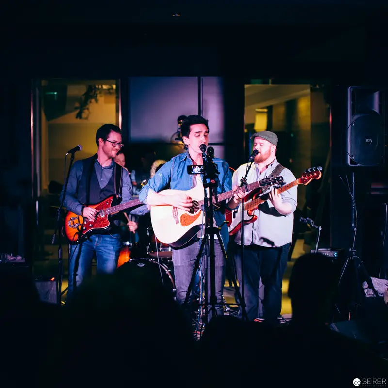Three-Piece Folk Band Performing Intimate Live Set with Acoustic Guitar and Electric Instruments