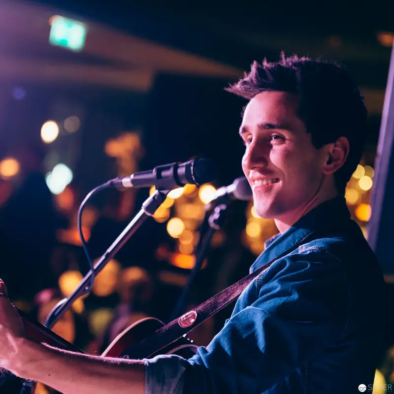 Musician Performing Live with Acoustic Guitar Under Warm Stage Lighting