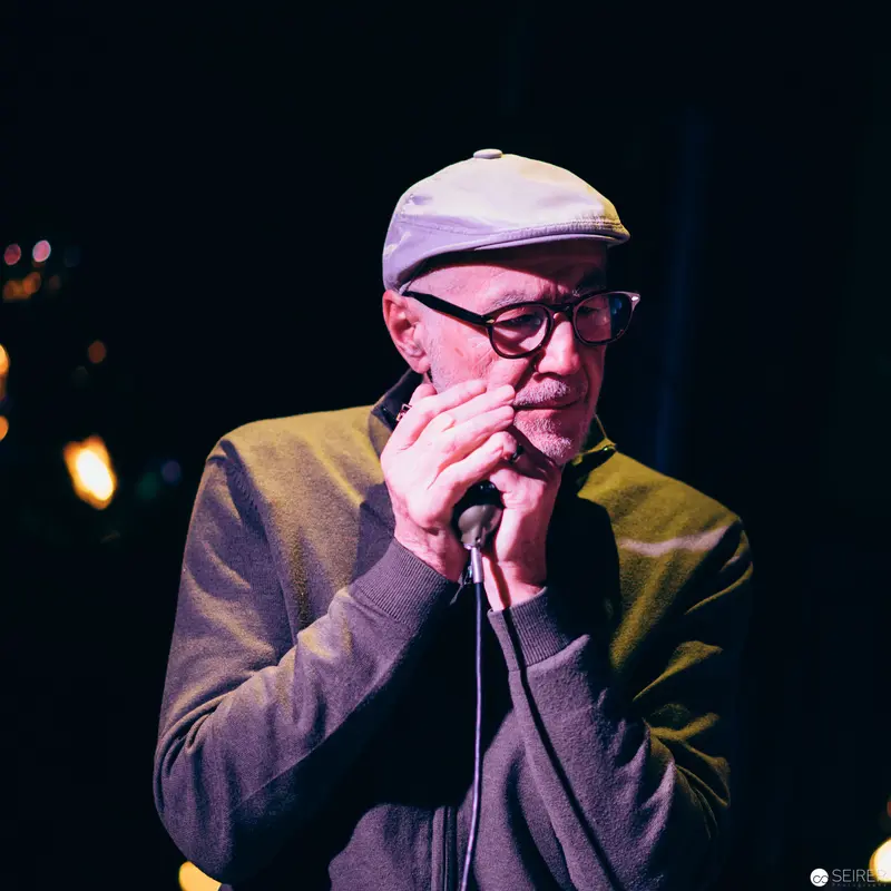 Intimate Performance: Vocalist in Soft Stage Lighting Wearing Flat Cap and Glasses