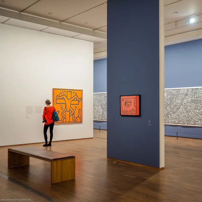Gallery Interior with Orange Keith Haring-Style Artwork and Visitor