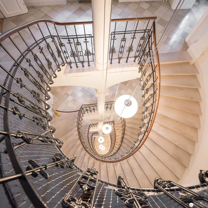 Spiral Staircase with Ornate Wrought Iron Railing and Suspended Globe Lights