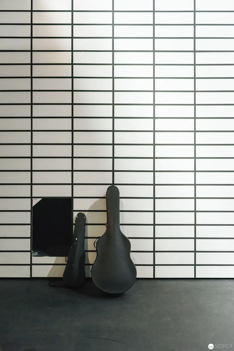 Minimalist Composition with Guitar Case Against Grid-like Ceramic Wall