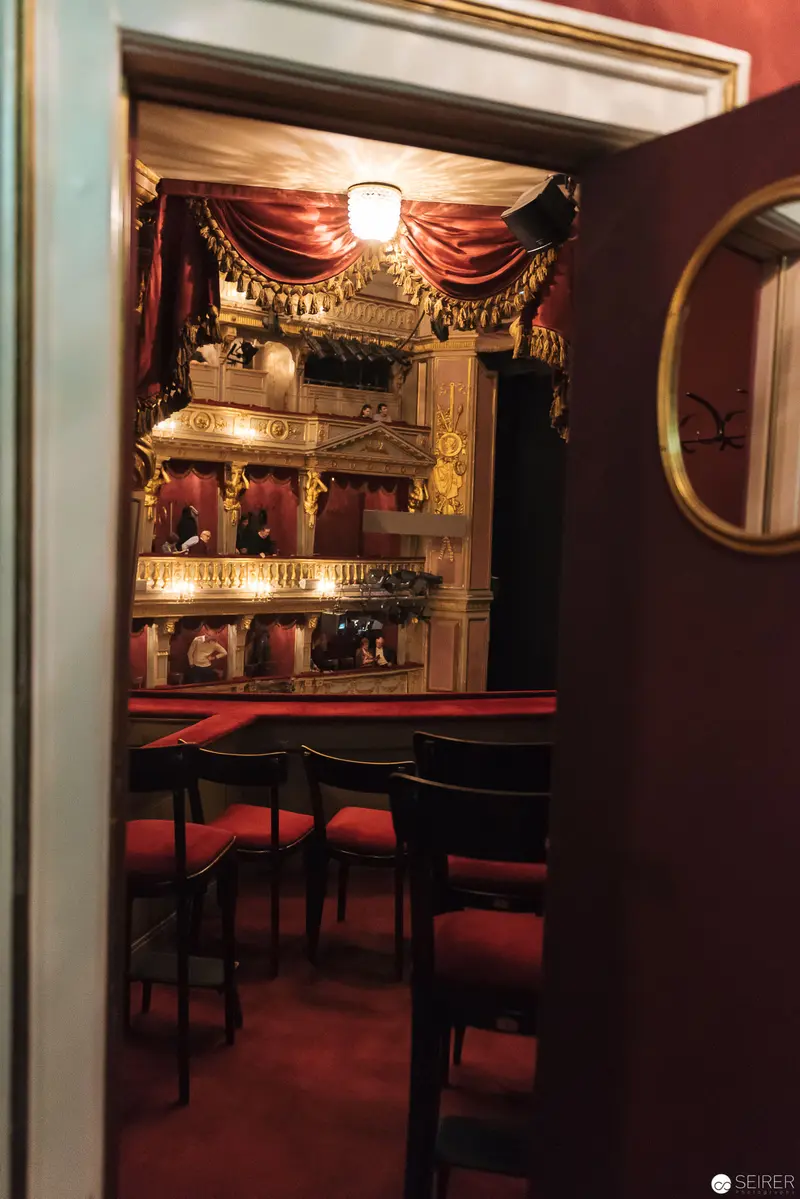 Intimate Theater Stage View with Ornate Red Curtains and Tiered Seating