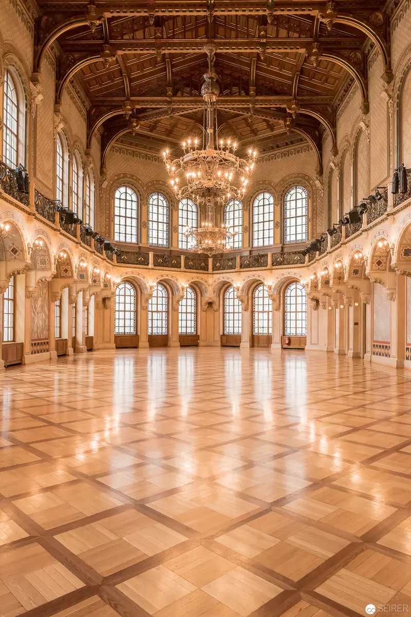 Grand Ballroom Interior with Ornate Chandelier and Herringbone Wood Flooring