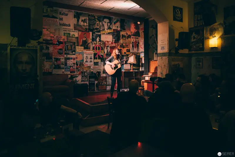 Acoustic Performance in Intimate Venue Surrounded by Concert Posters