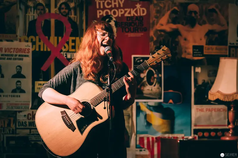 Acoustic Performance at Indie Venue with Vintage Poster Backdrop