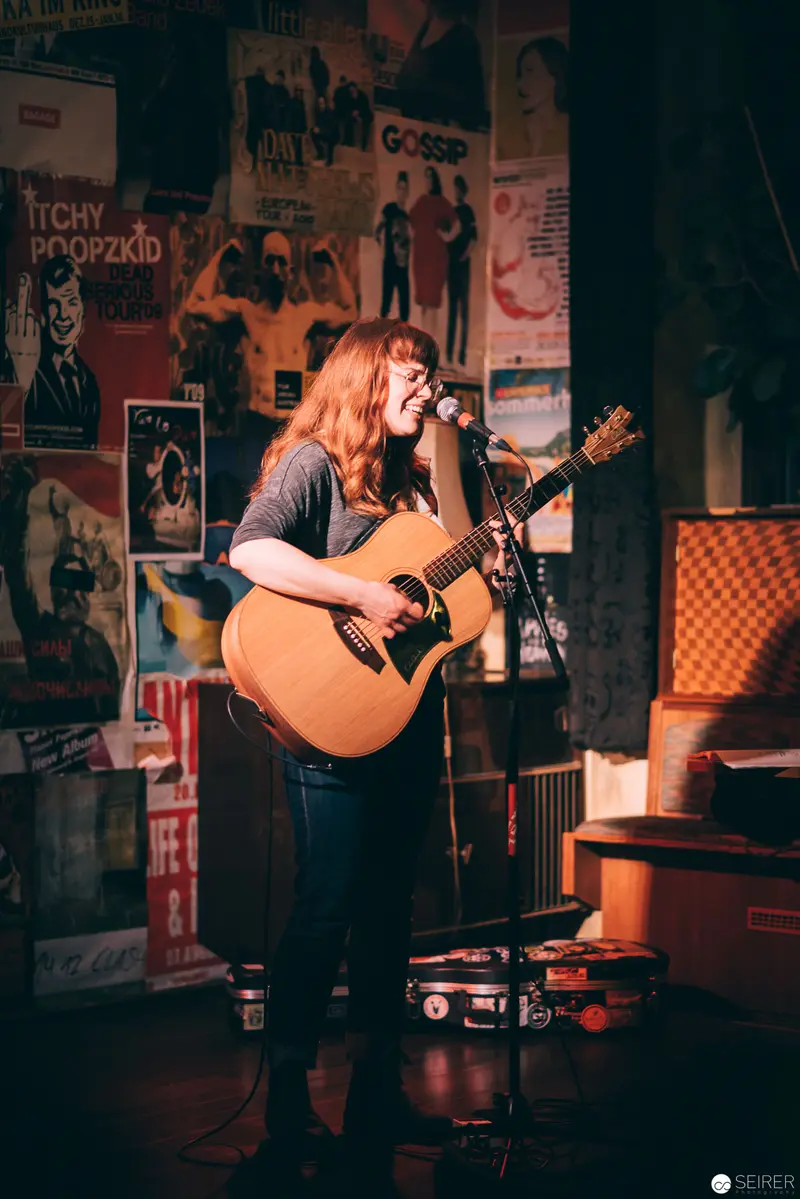 Solo Acoustic Performance in Vintage Music Venue with Concert Posters