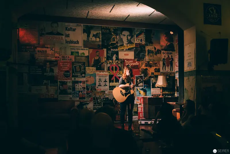 Acoustic Performance in Vintage Poster-Lined Music Venue