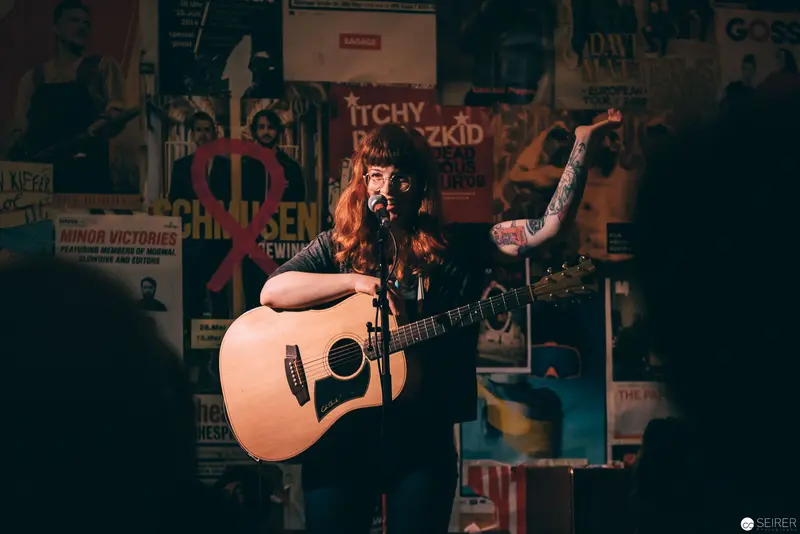 Acoustic Performer on Stage Amid Vintage Concert Posters
