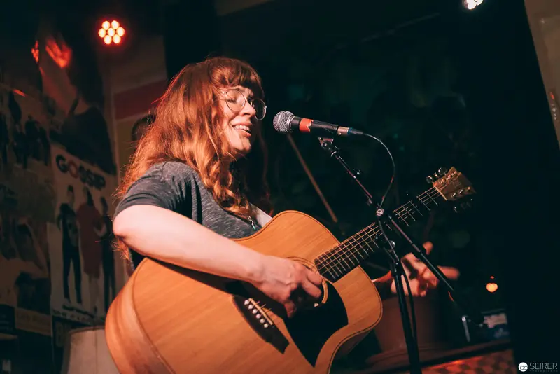 Acoustic Performer on Stage with Warm Overhead Lighting