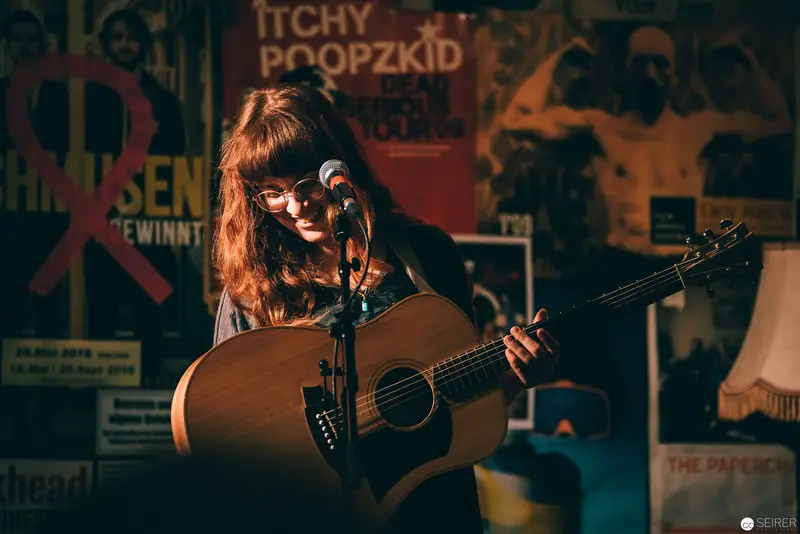 Acoustic Performance in Intimate Venue Surrounded by Vintage Posters