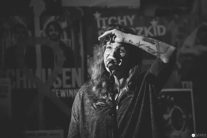Black and White Portrait of Long-Haired Individual in Grungy Urban Setting
