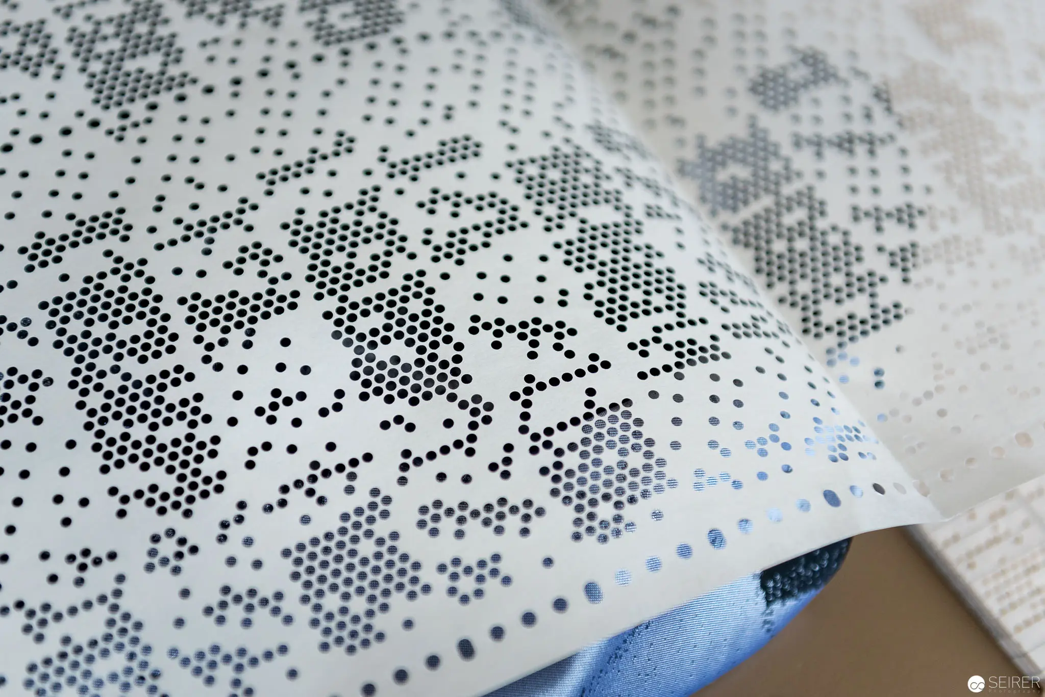 Perforated Geometric Pattern on White Surface with Gradient Blue Accent