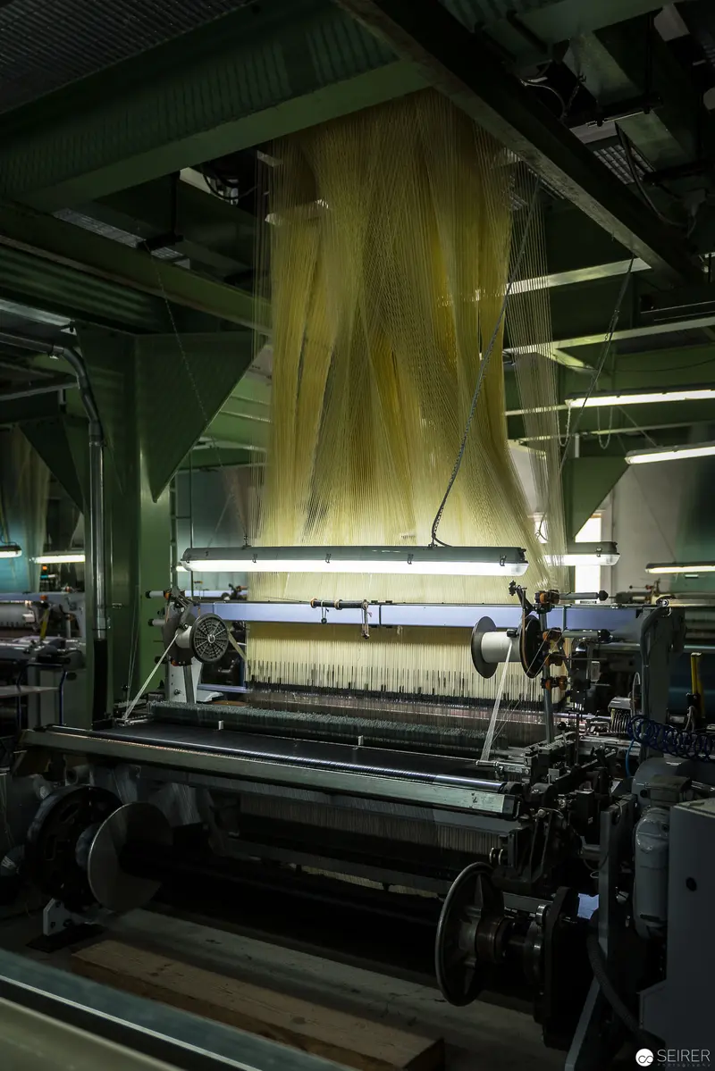 Industrial Textile Machinery: Illuminated Weaving Loom in Manufacturing Facility