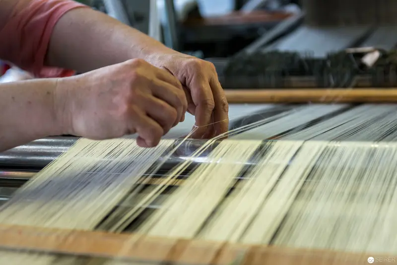 Artisan's Hand Weaving Traditional Textile on Intricate Loom Mechanism