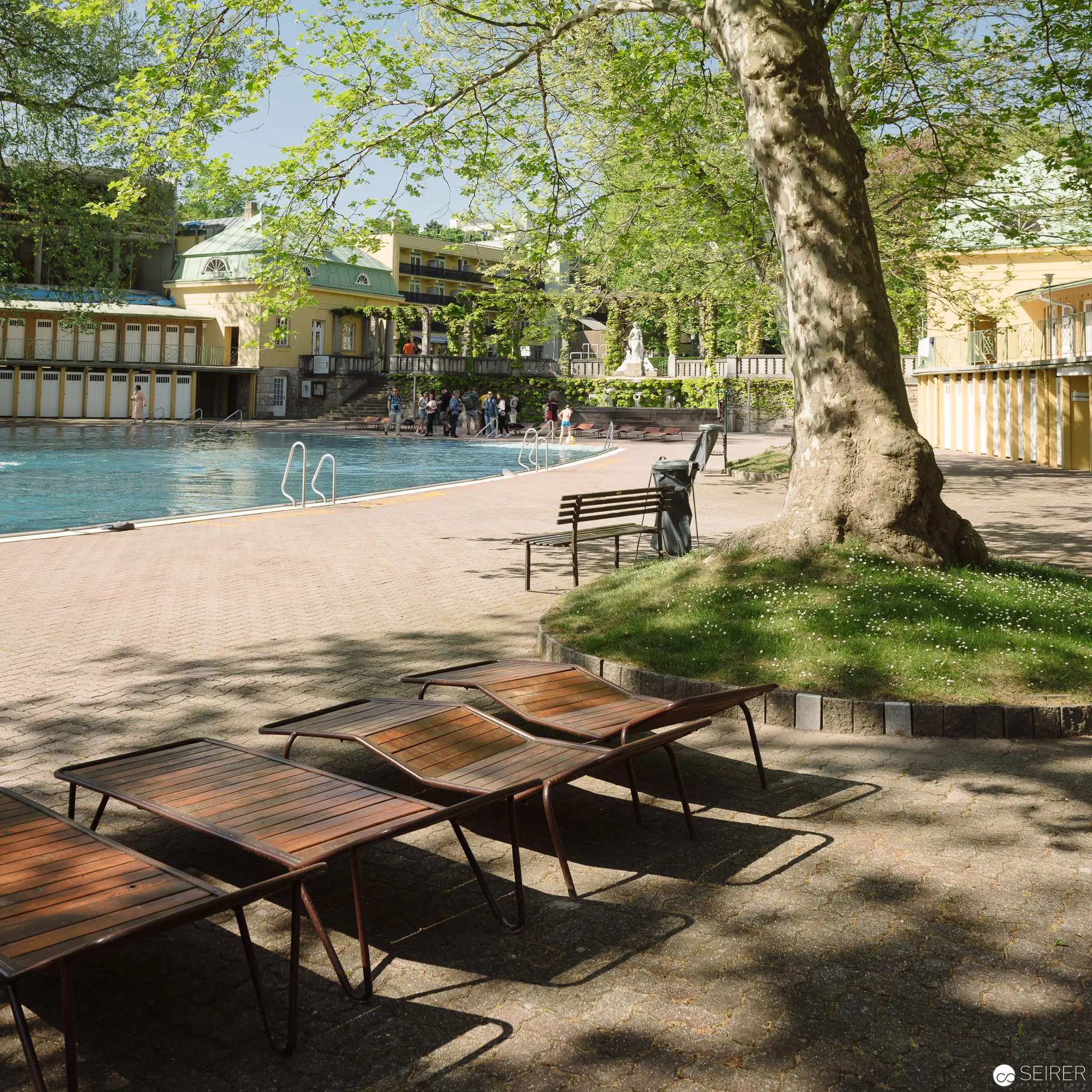 Sunlit Poolside Sanctuary at Thermalbad Bad Vöslau, Wooden Loungers in Foreground
