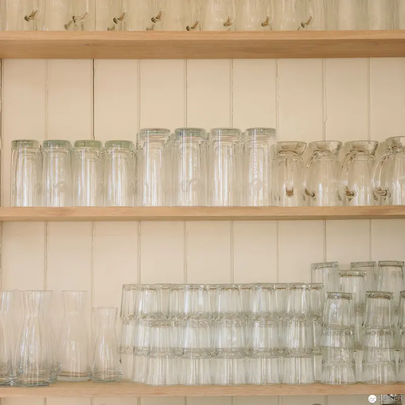 Meticulously Arranged Glassware on Wooden Kitchen Shelves in Neutral Tones