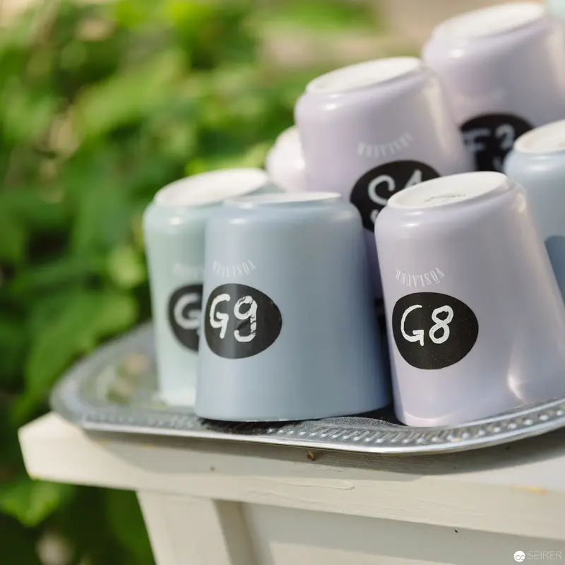 Numbered Ceramic Coffee Cups Arranged on Decorative Silver Tray with Botanical Background