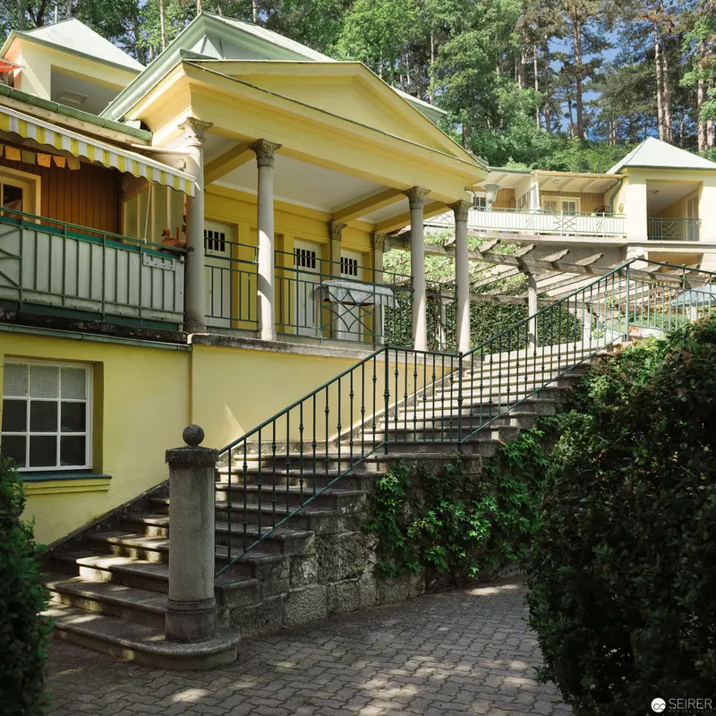 Yellow Villa with Elegant Stone Staircase in Serene Landscaped Setting