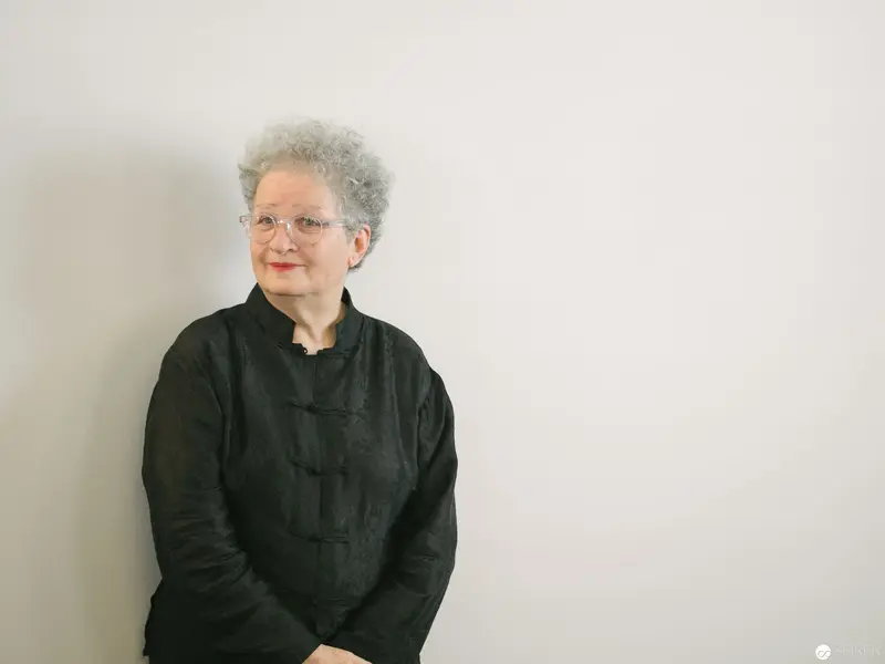 Elegant Senior in Black Traditional Asian-Style Jacket Against Neutral Background