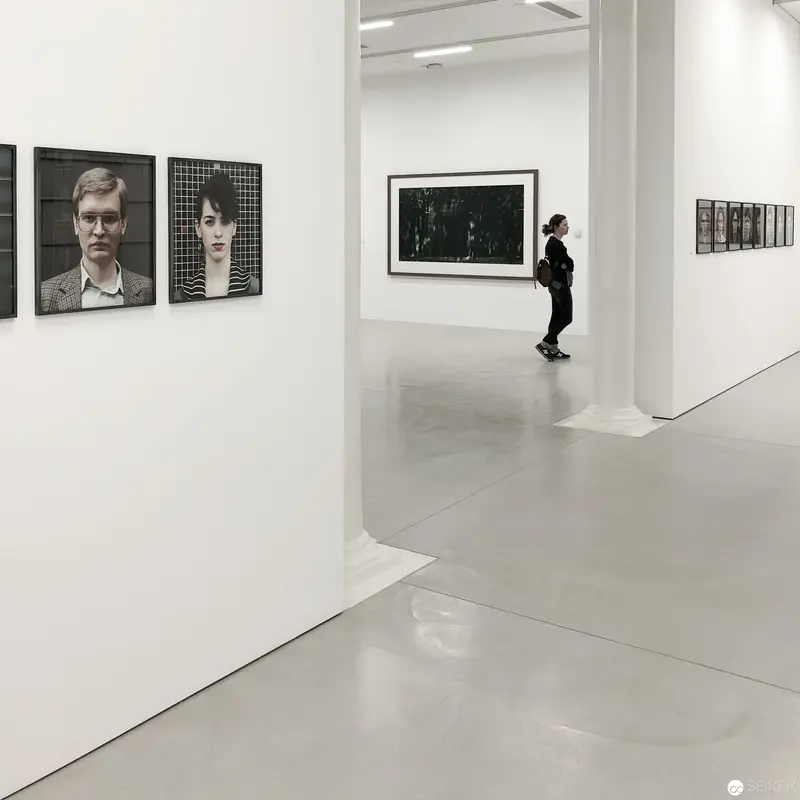 Monochromatic Gallery Interior with Photographic Portraits and Contemplative Viewer